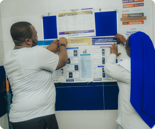 Two people reviewing immunization information on a clinic noticeboard